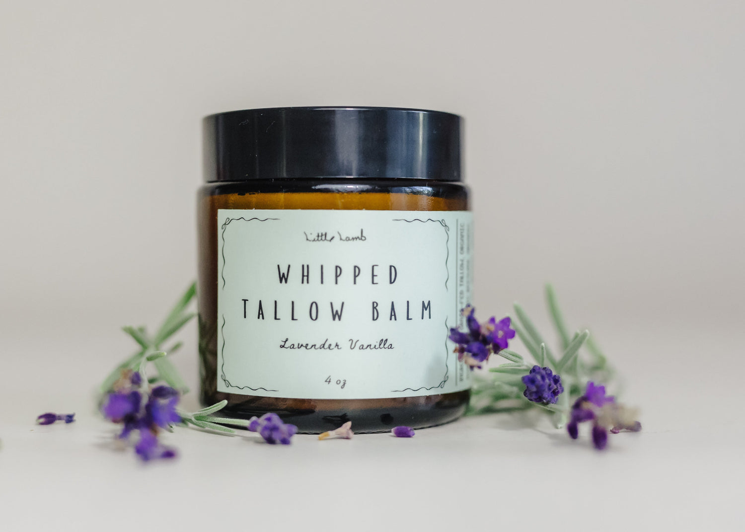 Jar of whipped tallow balm with lavender flowers on a light background