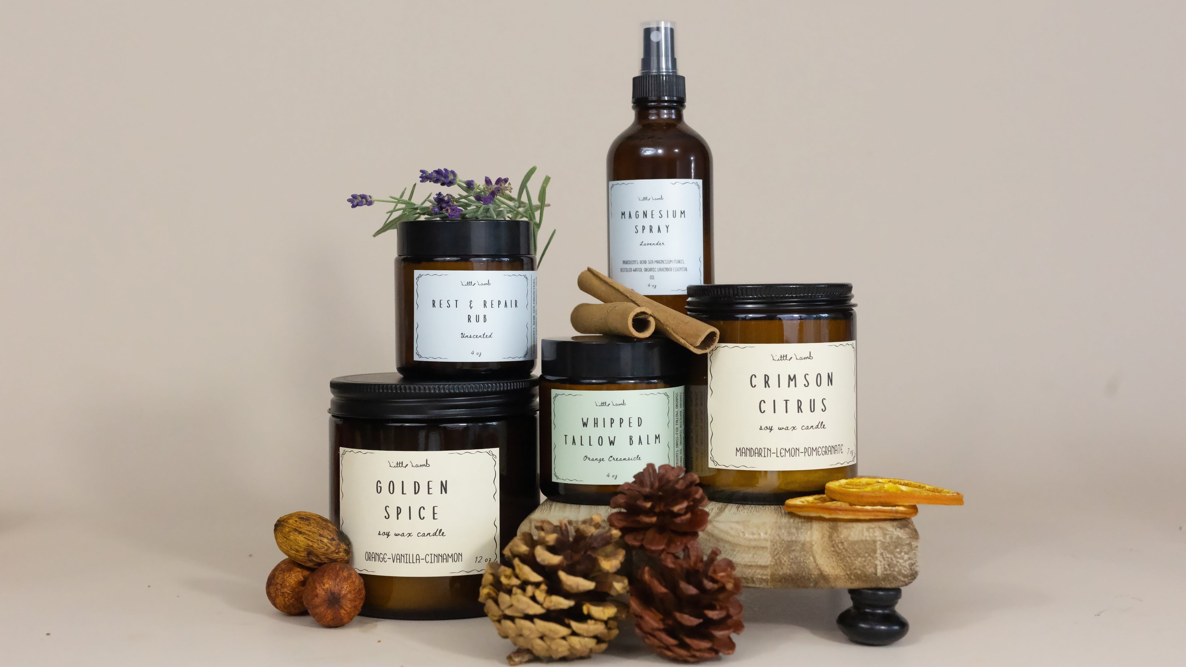 Collection of candles and a bottle on a wooden stand with a neutral background