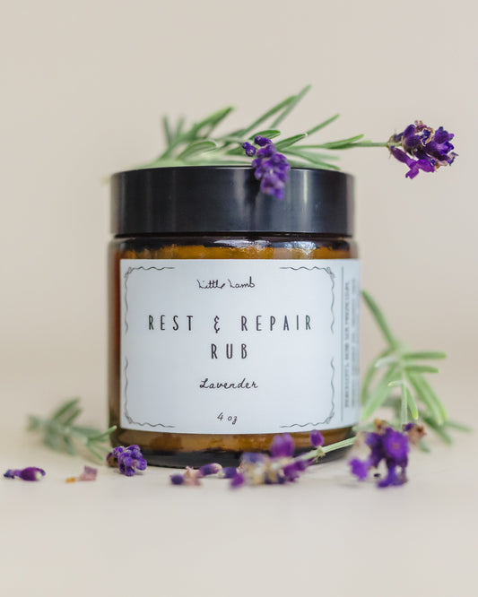 Jar of 'Rest & Repair Rub' with lavender flowers on a light background