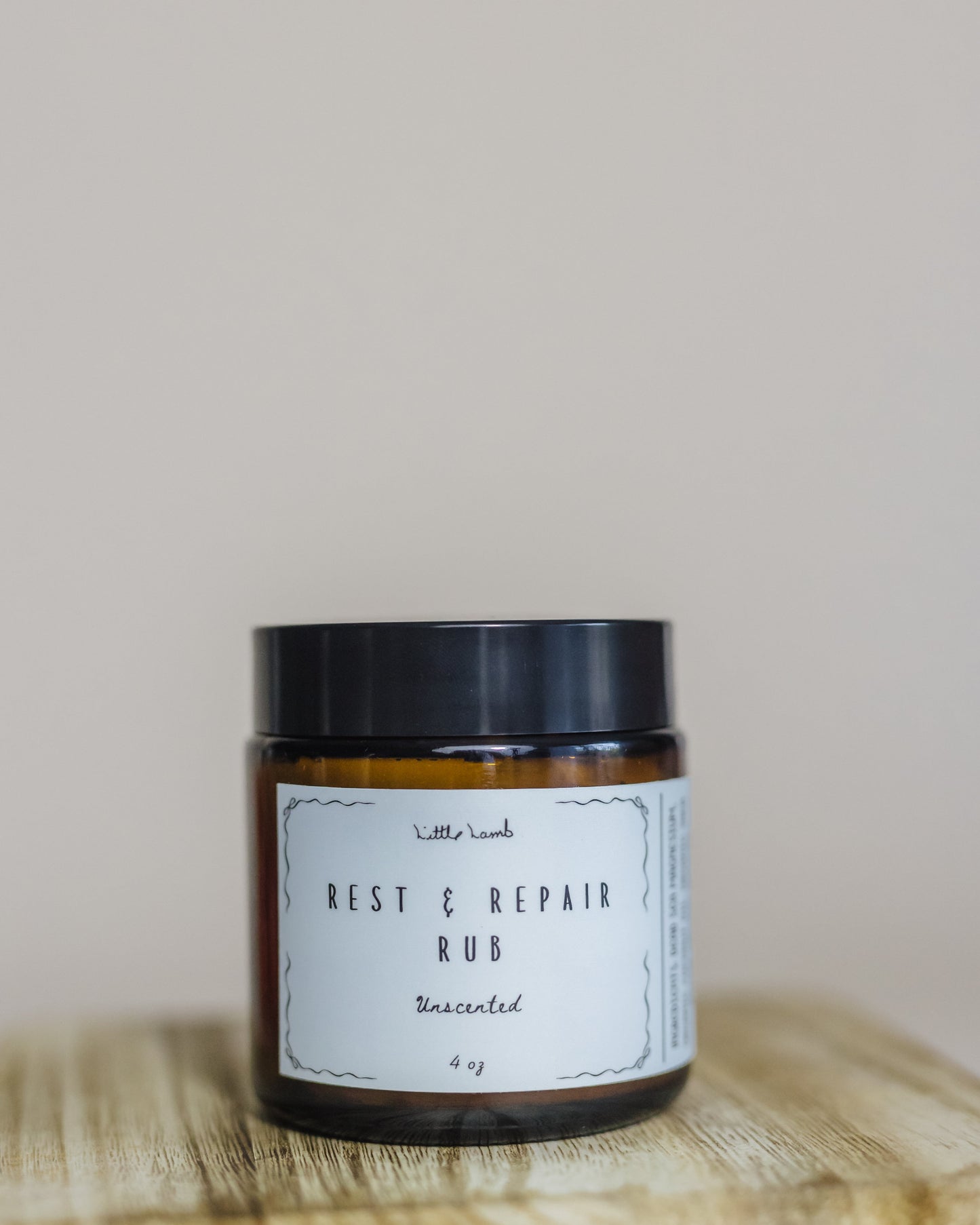 Jar of 'Rest & Repair Rub' on a wooden surface with a neutral background