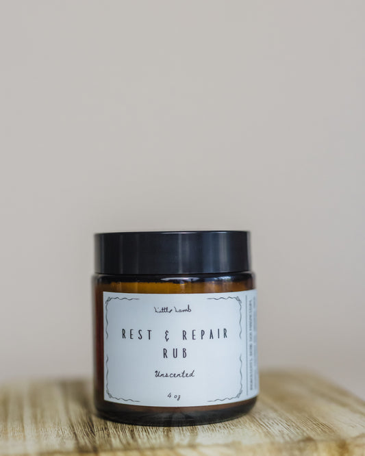 Jar of 'Rest & Repair Rub' on a wooden surface with a neutral background