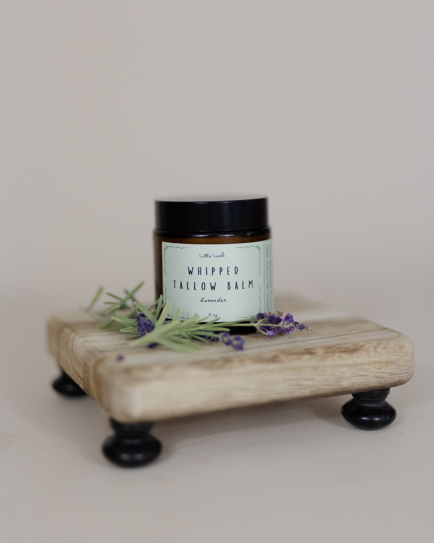 Jar of whipped tallow balm on a wooden stand with lavender flowers on a light background