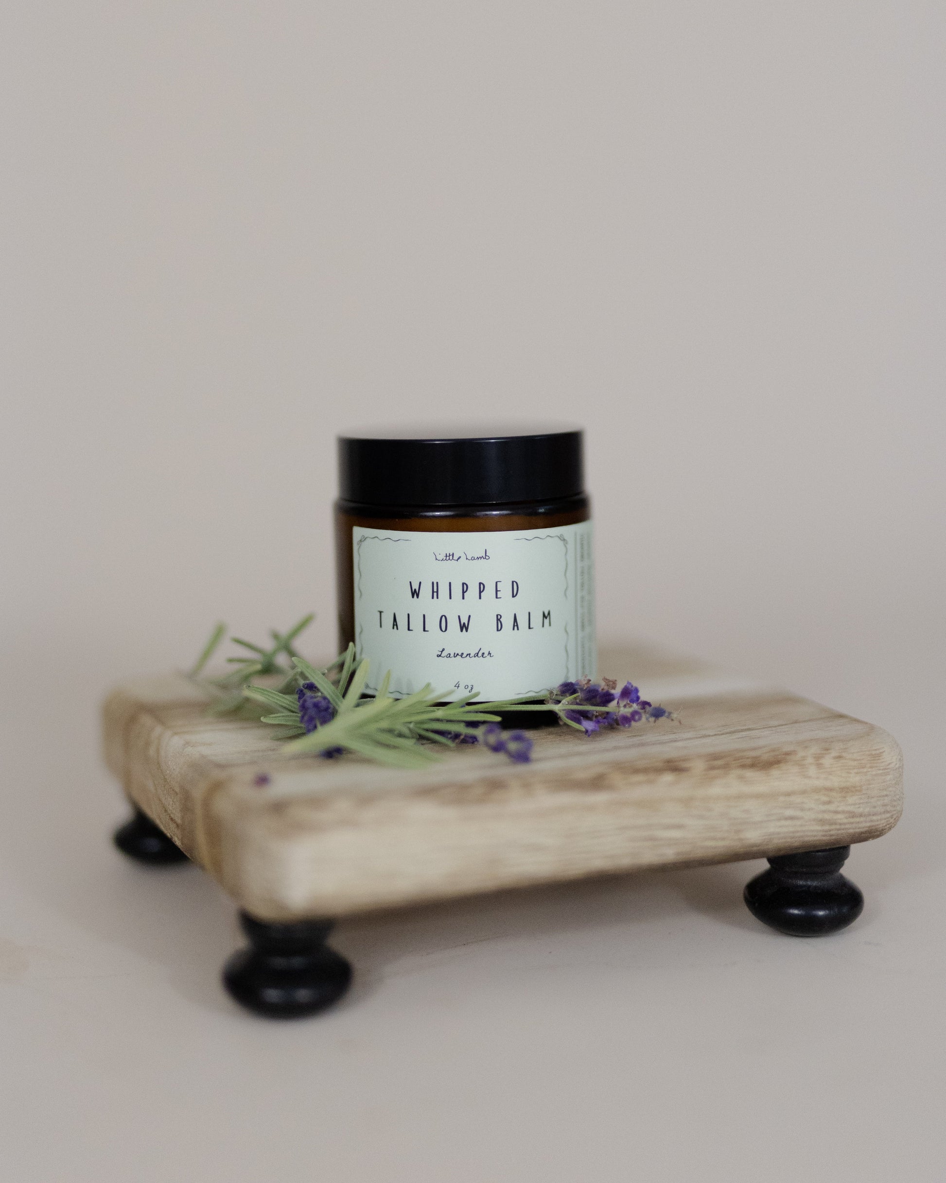 Jar of whipped tallow balm on a wooden stand with lavender flowers on a light background